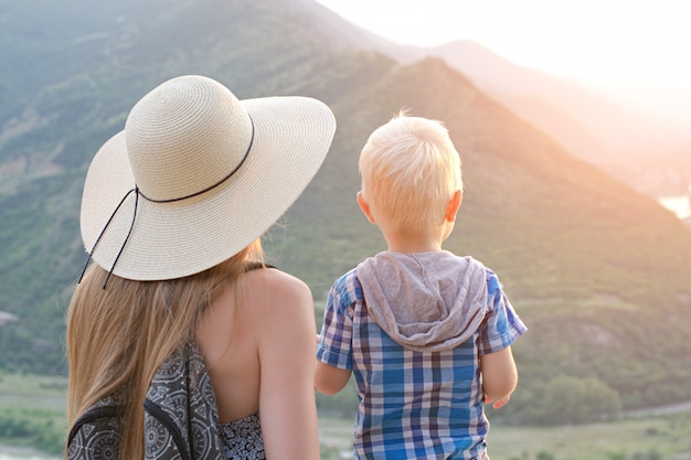 Mom and son stand on the green mountains