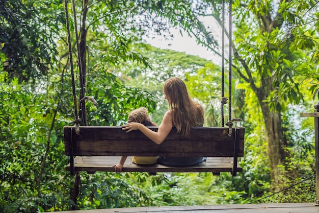 Mom and son on a swing in a tropical garden