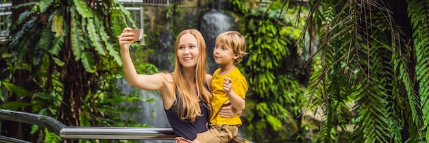 Mom and son take a selfie on the background of a waterfall banner long format