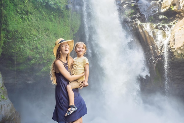 Mom and son tourists on the background of a waterfall Traveling with kids concept What to do with children Children friendly place