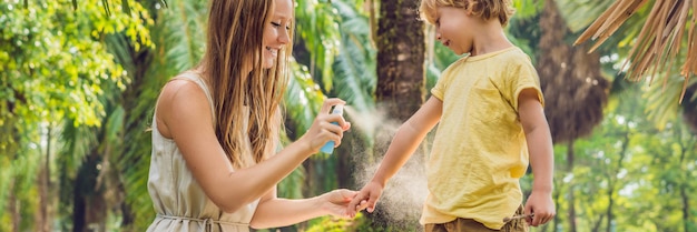 Mom and son use mosquito sprayspraying insect repellent on skin outdoor banner long format