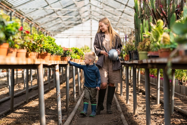 Mom and son walk in greenhouse with plants