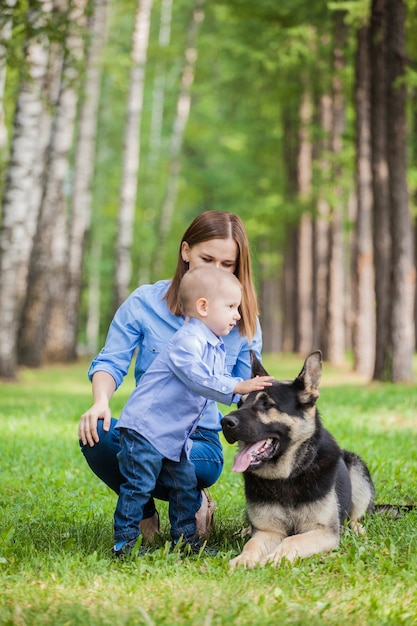 Mom and son on a walk with a shepherd dog in the forest