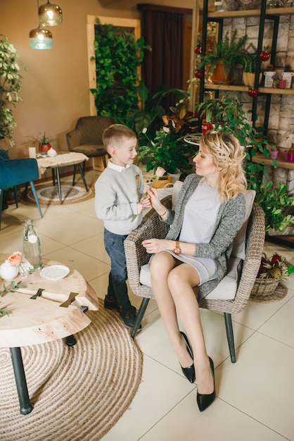 Mom and son with flowers in caffe. Son give flowers to mother. cute family. International women`s day, 8 march celebrating