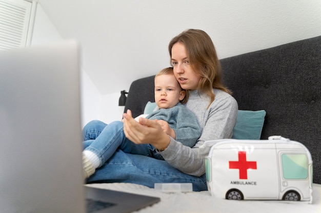 Photo mom taking care of her child and teleconsulting with doctor