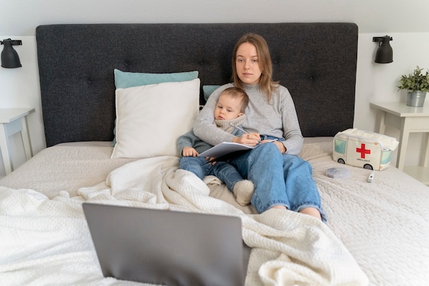 Foto mamma si prende cura di suo figlio e si teleconsulta con il medico