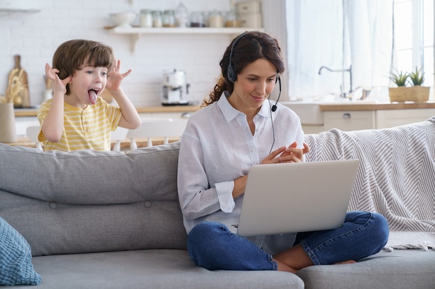 Mamma parlando in videochiamata lavoro remoto sul laptop da casa con il bambino