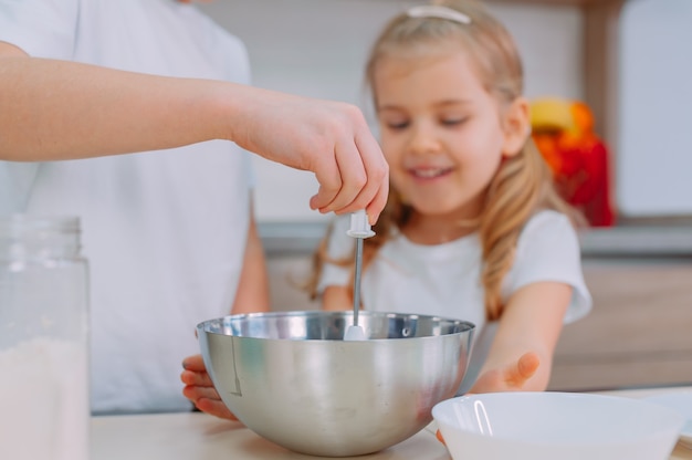 Mom teaches her daughters to cook dough in the kitchen.