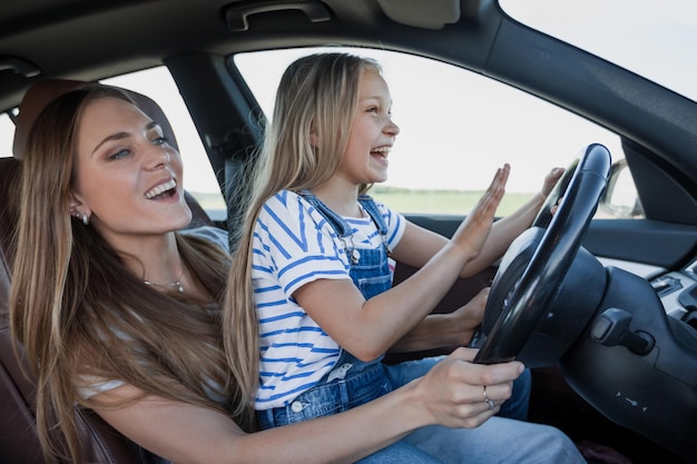 Mom teaches her little daughter to drive.the concept of parenting