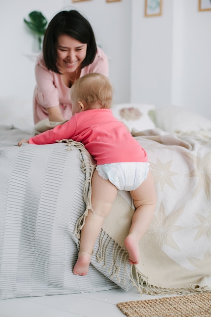 Mom teaches her little daughter to safely go down from the edge of the bed to the floor