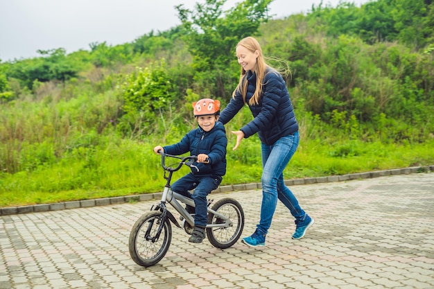 Mom teaches son to ride a bike in the park.