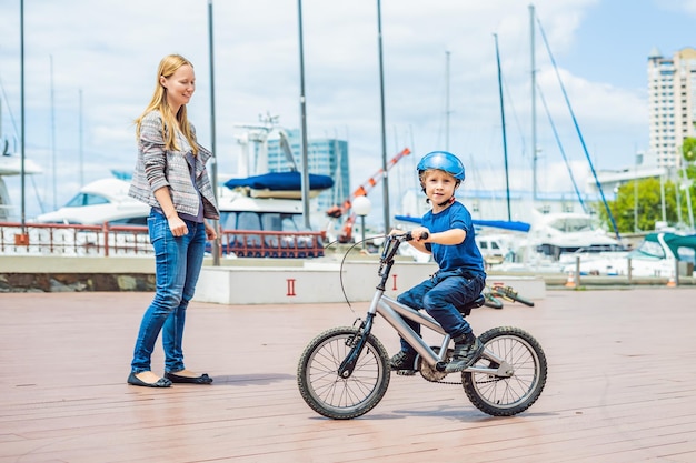 Мама учит сына кататься на велосипеде в парке