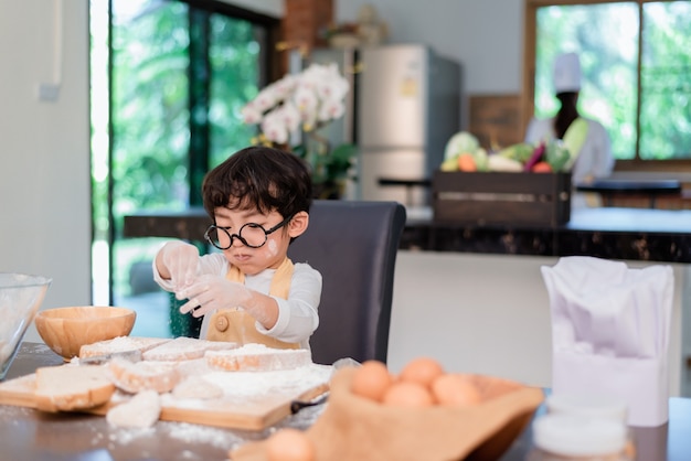 Мама учит сына готовить еду. Ежедневный образ жизни матери и ребенка дома. Азиатская семья вместе на кухне.