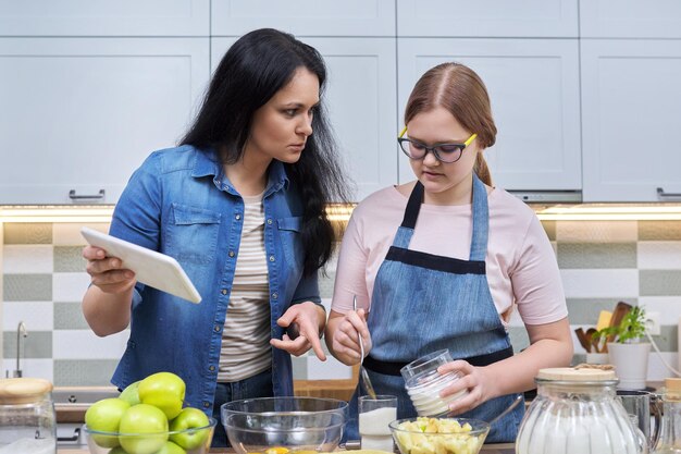 Мама и дочь-подросток вместе готовят яблочный пирог