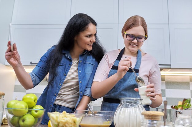 Mom and teenage daughter preparing apple pie together