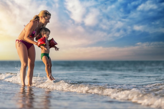 暖かい太陽の下で夏休みにママは息子を海の上に投げます