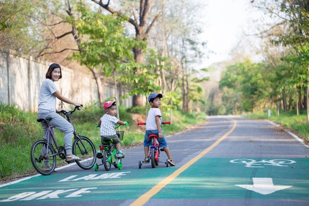 Mamma e due figli stanno andando in bicicletta sulla pista ciclabile.