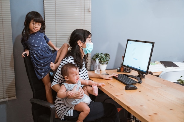 Mom wearing masks carrying her baby working home