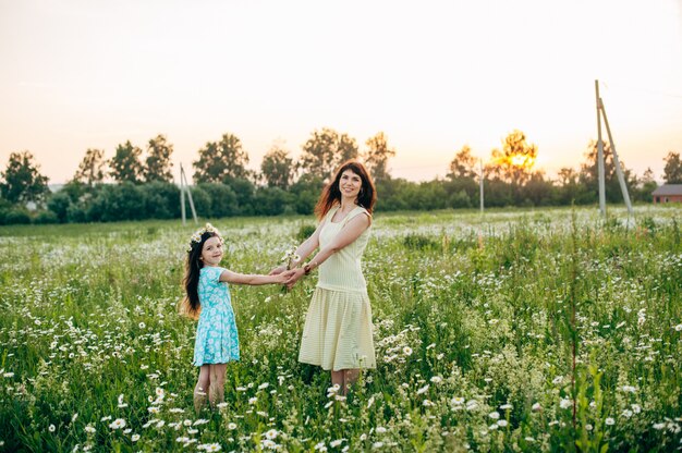 Mom with baby in daisy field at sunset. Toning