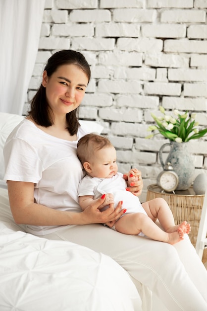 Mom with baby daughter sitting on the bed