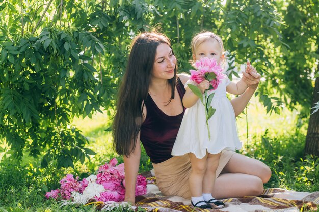 화창한 날에 그녀의 팔에 아기와 엄마는 공원을 안내합니다.