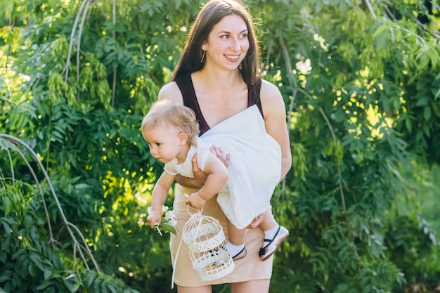 Mom with a baby in her arms on a sunny day walks through the park.