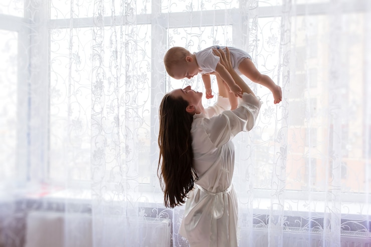 Photo mom with baby near the bedroom window