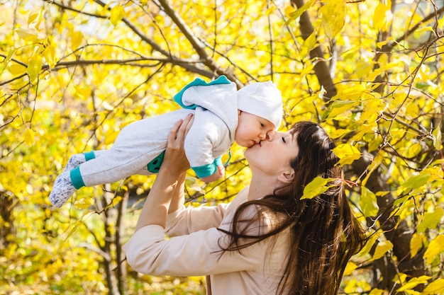 Mamma con un bambino, un bambino cammina in autunno nel parco o nella foresta. foglie gialle, la bellezza della natura. comunicazione tra un bambino e un genitore.