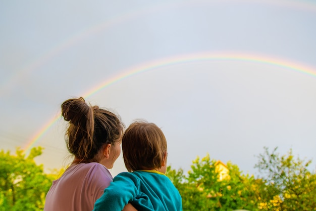 子供を持つお母さんが虹を見ます。ママと息子の母性の背景。虹を見てください。