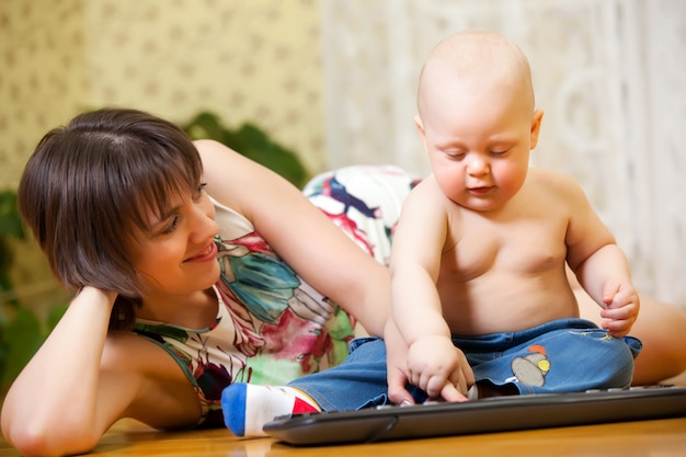 Mom with child playing with keyboard on floor