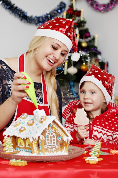 Mom with daughter prepare gingerbread house