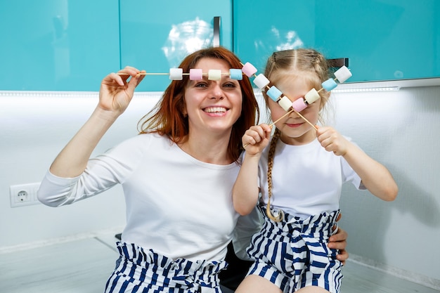 Mom with daughter in the turquoise kitchen eat marshmallows. lovely family relationships. happy family concept, happy parents and children