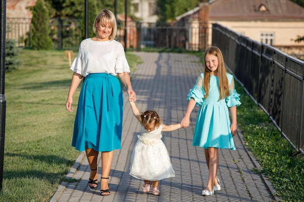 Mom with daughters walks in the park in summer. family walk