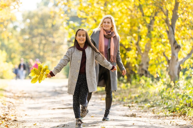 Mom with her daughter during autumn.