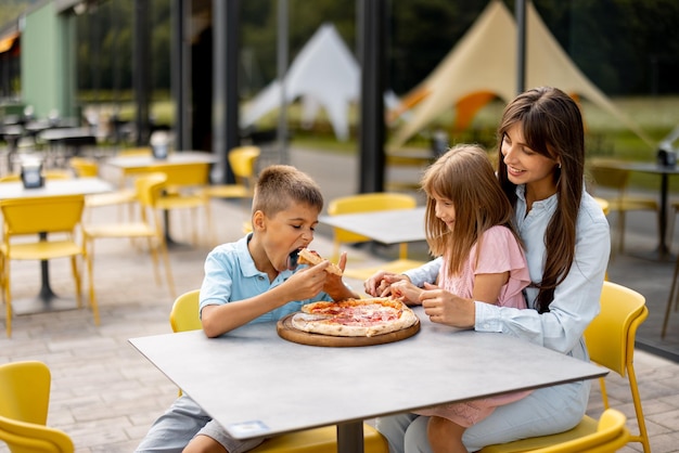 遊園地でピザを食べる子供を持つお母さん