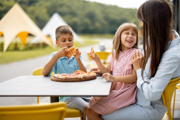 遊園地でピザを食べる子供を持つお母さん