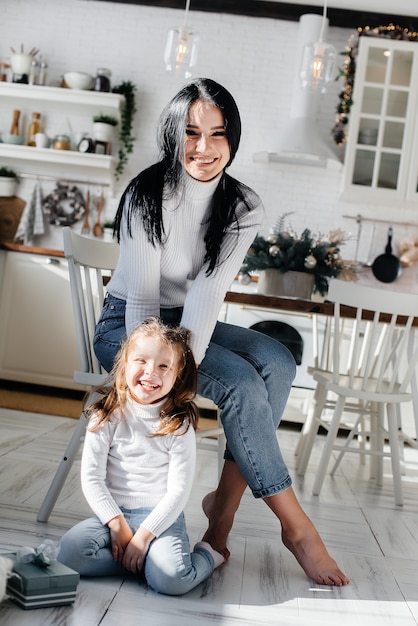 Mom with a little girl unpack gifts. Holiday.