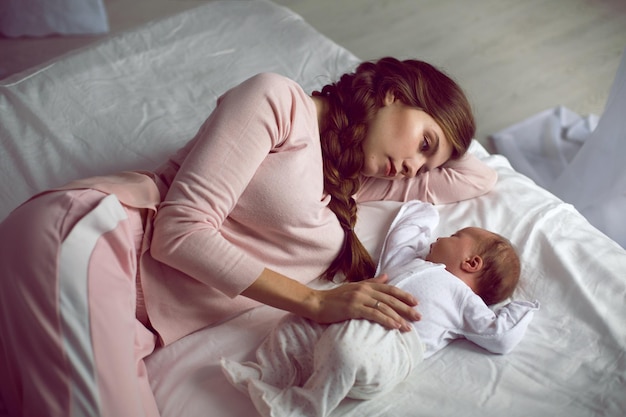 Foto mamma con una piccola figlia neonata sdraiata sul letto nella camera da letto