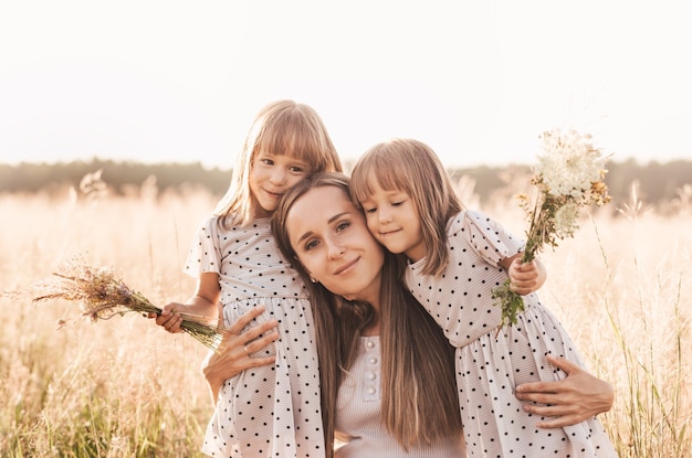 Mom with two twin girls playing in nature in the summer