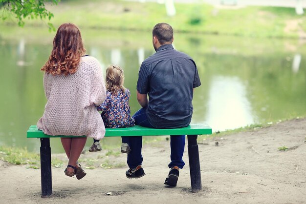 Мама и маленькая дочь и папа, молодая семья на прогулке в парке летом
