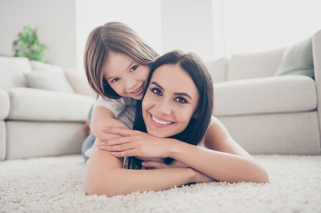 Mommy cuddle her kid girl on carpet in room light apartment