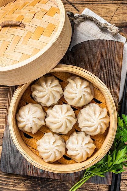 Momo dumplings in a bamboo steamer. Wooden background. Top view.