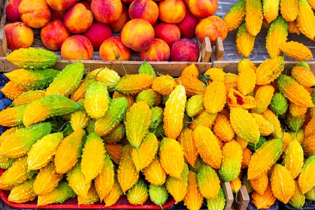 Momordica en perziken bij de fruitkraam Verkoop van seizoensfruit