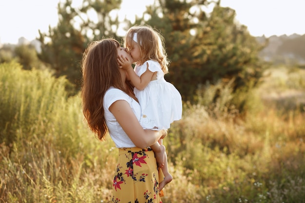 Mamme e figlia in natura si baciano durante la passeggiata estiva