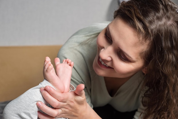 Moms love for the baby brunette woman holding legs of baby