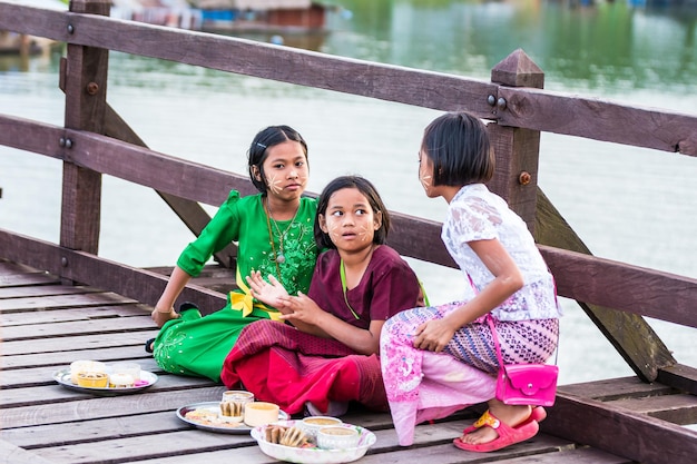 Mon boys and girls selling flowers on a wooden bridge over the river