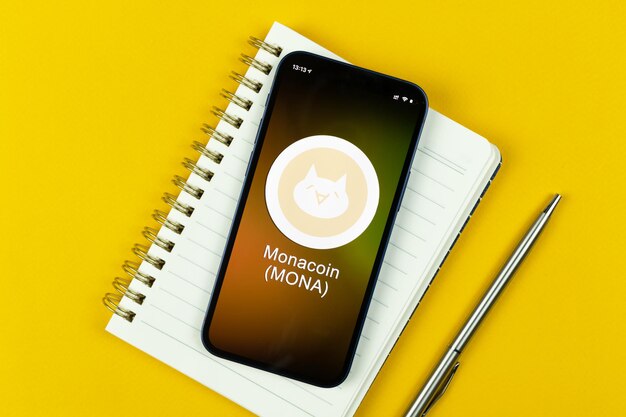 Monacoin symbol. Trade with cryptocurrency, digital and virtual money, banking with mobile phone concept. Business workspace, table top view photo