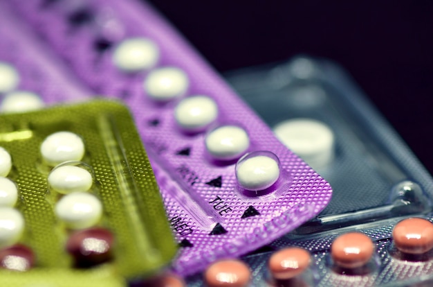 Mondelinge contraceptieve pil op zwarte achtergrond.