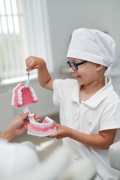 Mondgezondheid tandarts jongetje in medisch pak. Mondeling tandheelkundig uniform voor kinderen.