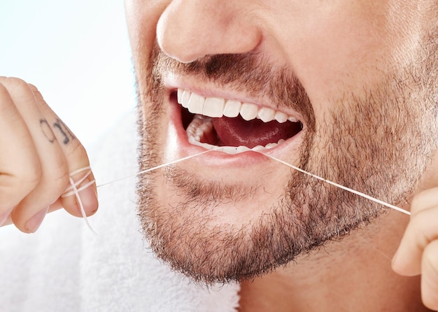 Mondhygiëne en man zijn tanden flossen in een studio voor mondverzorging, verzorging of gezondheid Wellness gezond en close-up van mannelijk model doet frisse, schone en natuurlijke mondroutine door witte achtergrond